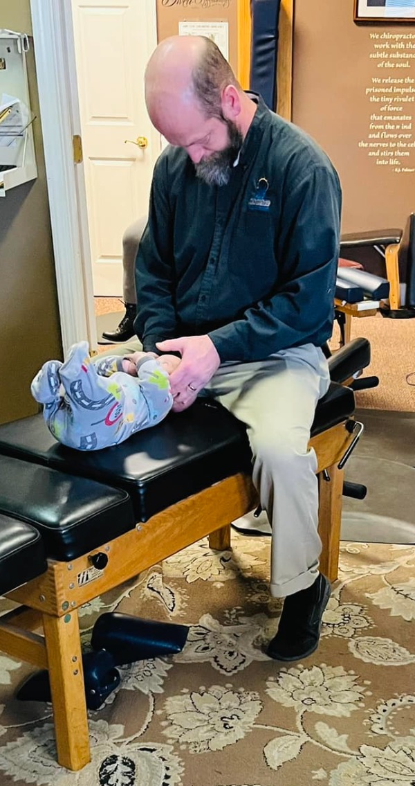 Dr. Kevin Laucher gently adjusting an infant patient at Providence Family Chiropractic in Lansing, MI